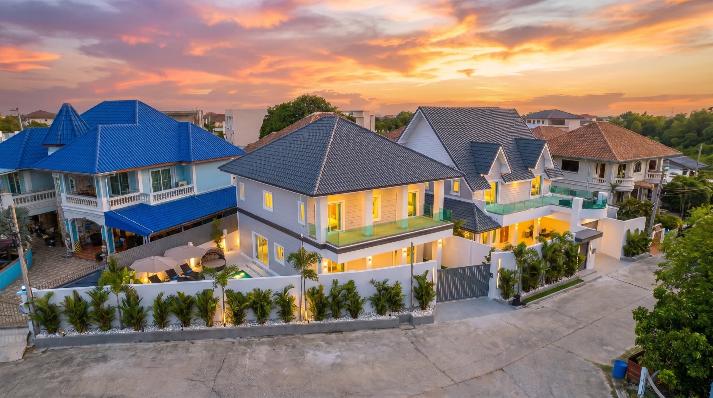 Villa Azure at twilight — the full compound from above, both wings under a sunset sky behind the walled gate.